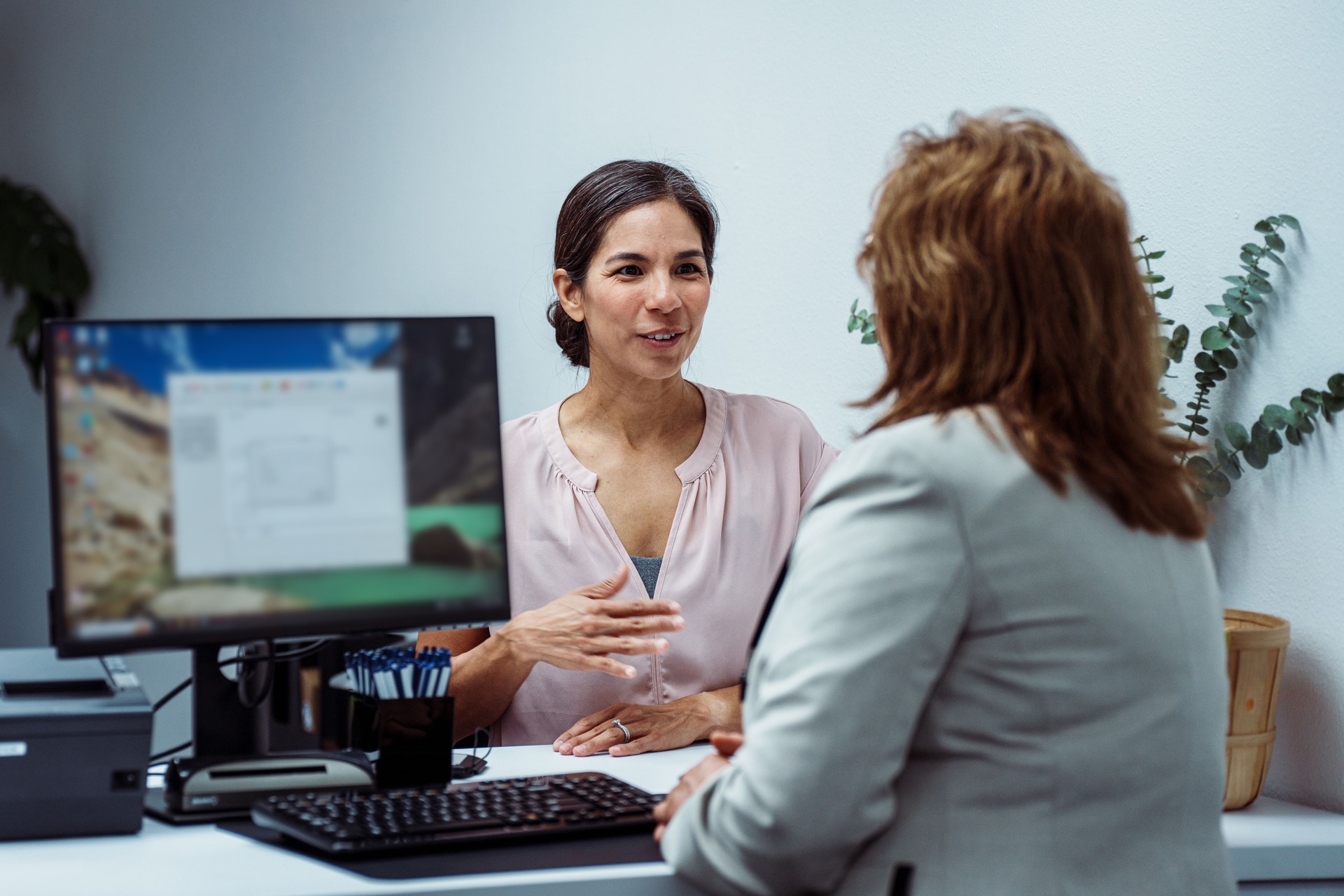 Mexican woman talking with customer service representative at reception desk