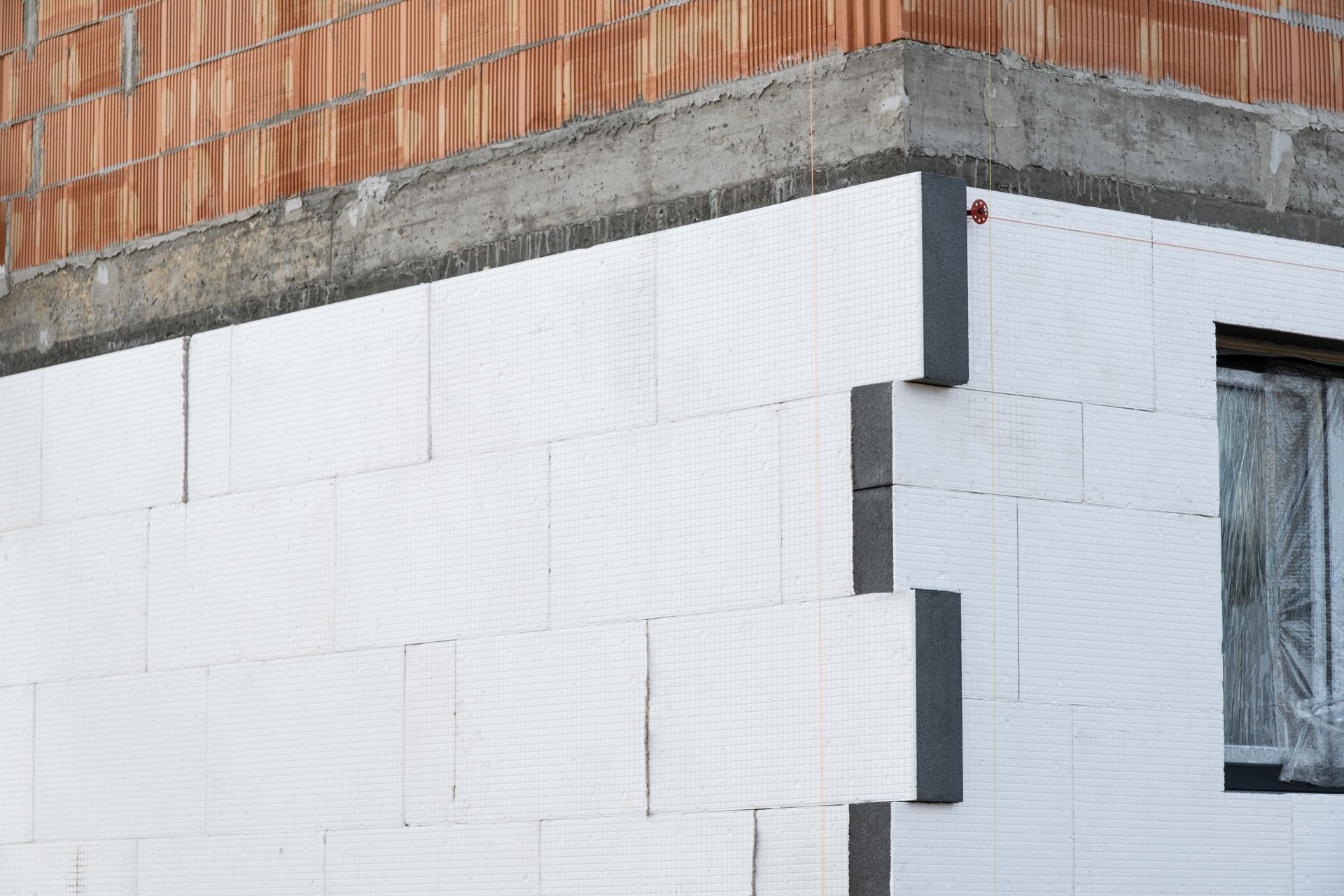 building facade under construction is covered with insulation panels. The thermal insulation is installed over a brick and concrete structure